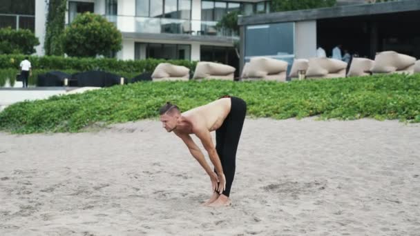 Atletisk bar överkropp man göra stretchingövningar yoga på sandstrand — Stockvideo