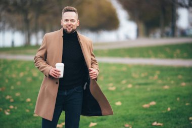 Park, kopya alanı Kupası içme kahve yakışıklı sakallı genç adam