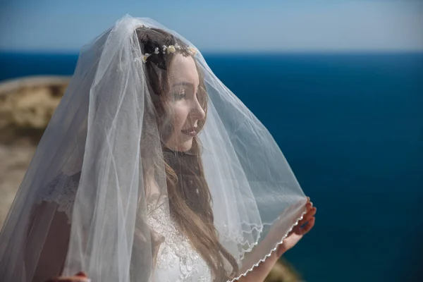 Gyönyörű menyasszony, fátyol, háttérben az óceán portréja — Stock Fotó