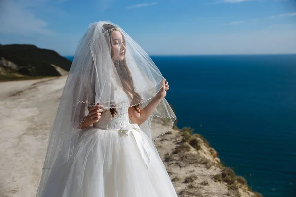 Gyönyörű menyasszony, fátyol, háttérben az óceán portréja. — Stock Fotó