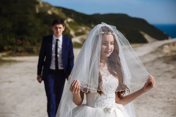 Sposa in abito bianco con velo sul viso è in attesa per lo sposo che arriva dietro — Foto Stock