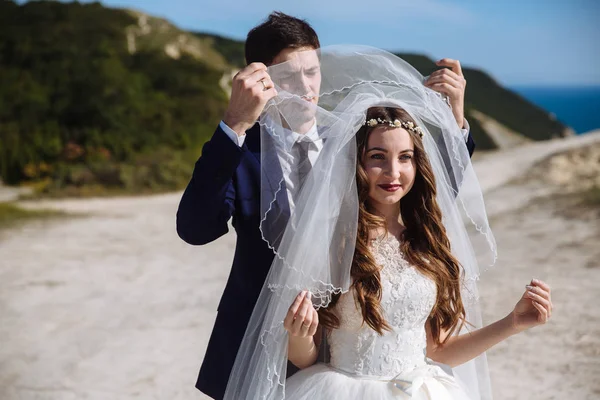 Sposo cammina alla sposa da dietro e risies velo dal suo viso — Foto Stock