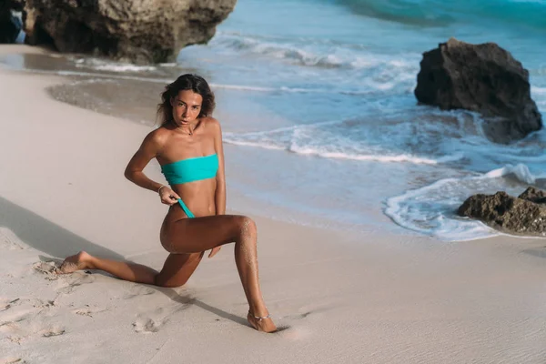 Сексуальная девушка в синем купальнике позирует в солнечный день на песчаном пляже — стоковое фото