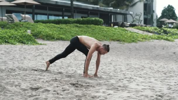 Jovem atlético praticando ioga na praia . — Vídeo de Stock