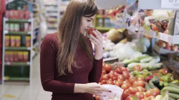 若い女の子は、スーパーの食料品部門で野菜を買うし、ビニール袋に入れます — ストック動画