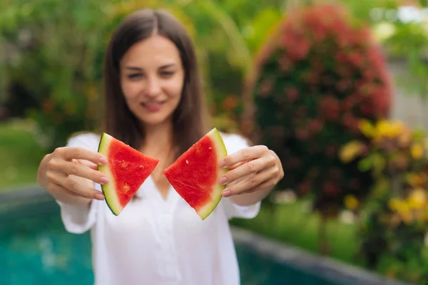 Close up of womans hands make butterfly shape from two pieces of watermelon with blurred girl on background — Stock Photo, Image