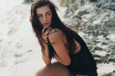 Seksi esmer modelinde örme kazak kumlu plaj, büyük taş ve kaya zemin üzerine poz portresi.