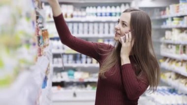 Gülümseyen, telefonda konuşurken ve süpermarkette alışveriş güzel kız