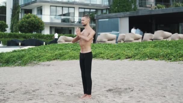 Sportos férfi csinál jóga póz és pilates gyakorlatok homokos strandon — Stock videók