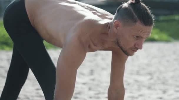 Lekkoatletycznego mężczyzna robi pozy i pilates ćwiczenia jogi na plaży — Wideo stockowe