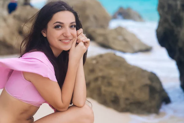 Primer plano retrato de linda chica con una hermosa sonrisa. Modelo con pelo largo y liso en traje de baño rosa en la playa —  Fotos de Stock