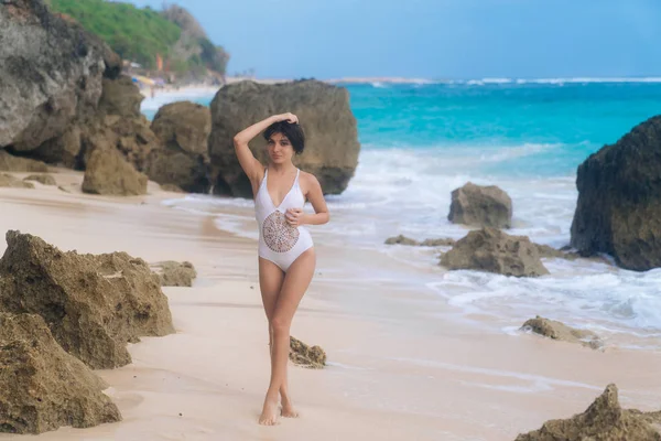 Сексуальная женщина в белых купальниках позирует и танцует на летнем отдыхе на скальном пляже — стоковое фото