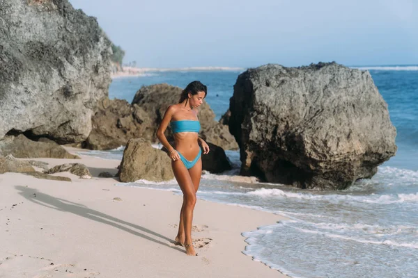 Sexig garvade flicka i blå baddräkt poserar på solig dag på sandstranden — Stockfoto