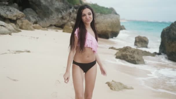 Медленные движения, портрет счастливой улыбающейся красивой девушки в купальнике отдыхающей на пляже, устойчивый снимок — стоковое видео