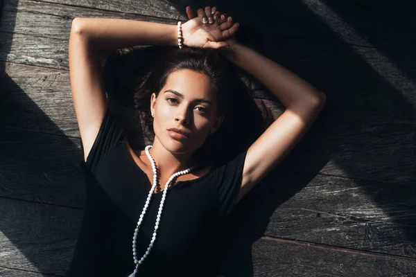 Top view portrait of beautiful sexy girl in black dress lying on wooden floor — Stock Photo, Image