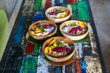 Dört smoothies kase kadar yakın mango, muz, granola, Hindistan cevizi rendesi, dragon meyve ile yapılmış, chia tohum ve nane renkli arka plan