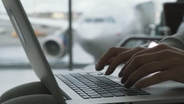 Las manos del primer plano de la mujer que trabaja en el portátil en el fondo de la sala del aeropuerto del avión en la ventana esperando el abordaje — Vídeos de Stock