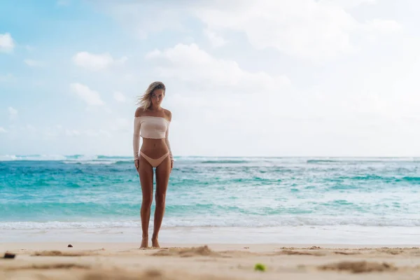 美丽的晒黑的女孩站在海滩上与白色的沙子和蓝色的海洋 — 图库照片