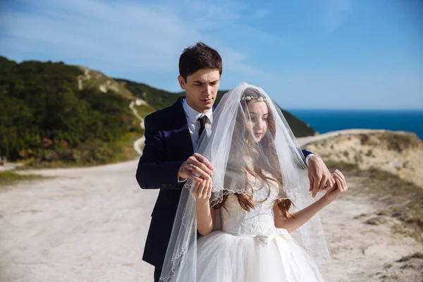 Sposo in tuta viene alla sposa da dietro e vuole sollevare il velo dal suo viso — Foto Stock