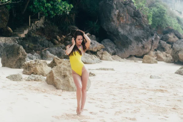 Красивая девушка в жёлтом купальнике гуляет по белым песчаным пляжам возле океана . — стоковое фото