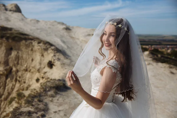 Portrét krásné nevěsty se závoji na tváři a v bílých svatebních šatech — Stock fotografie