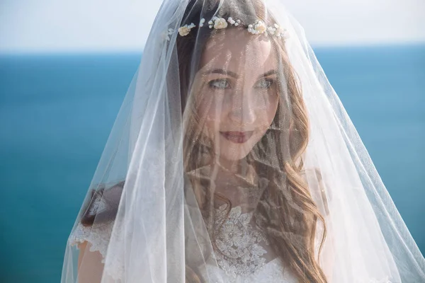 Gros plan portrait de mariée avec beau maquillage, coiffure et voile sur son visage avec fond océan — Photo