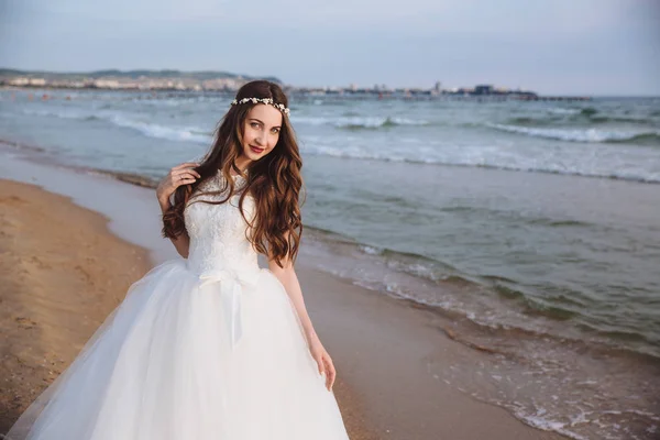 Retrato de noiva bonita em vestido de noiva elegante na praia do oceano. Noiva com penteado e maquiagem posando no dia do casamento — Fotografia de Stock