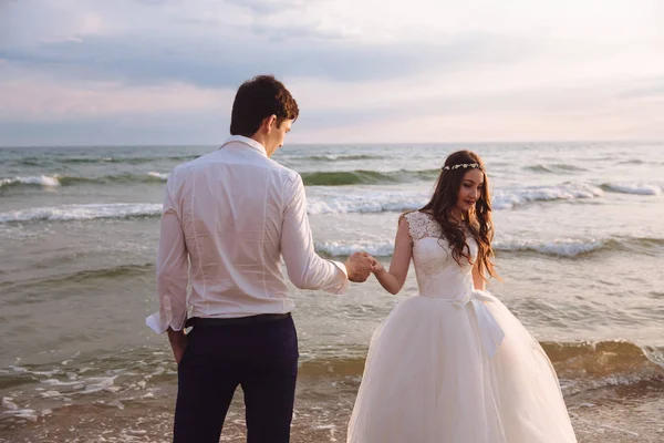 Elegancki Pan młody trzyma w ręce pięknej narzeczonej. Newlywed para na ocean plaża — Zdjęcie stockowe