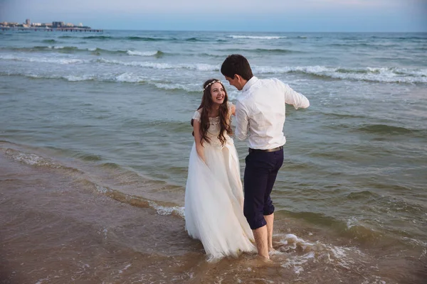 Sposa e sposo ridere e divertirsi sulla spiaggia dell'oceano. Felice coppia appena sposata — Foto Stock