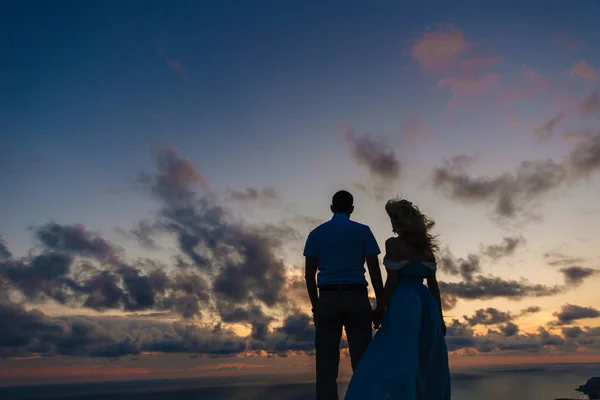 Silhouette di una coppia amorevole al tramonto. Un uomo che abbraccia una donna su un'alta montagna con vista sul mare. Concetto famiglia, amore, matrimonio, viaggio di nozze . — Foto Stock