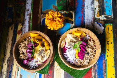 Mango, muz, granola, Hindistan cevizi rendesi, dragon meyve, chia tohum ve renkli arka plan üzerinde nane ile yapılan dört yüzlü kase kadar kapatın