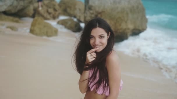 Повільний рух, портрет щасливої дівчини в купальнику, що розслабляється на пляжі з красивими хвилями на фоні, білий знімок . — стокове відео