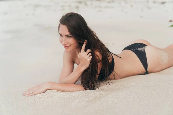 性感的晒黑女孩在沙滩上摆姿势在海边。美丽的模型日光浴和休息 — 图库照片