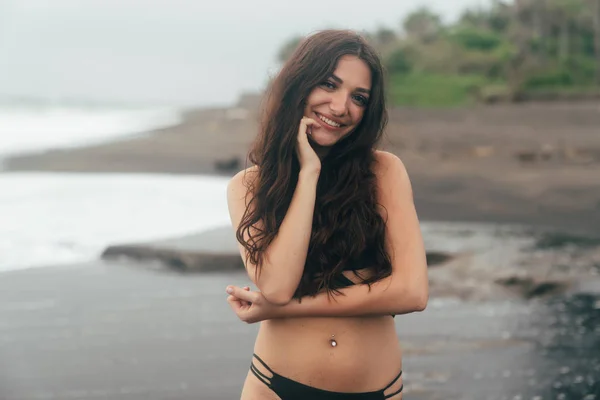 Retrato de menina bonita com cabelos longos em maiô posando na praia tropical com areia preta — Fotografia de Stock