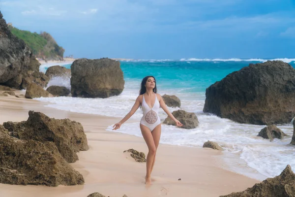 Красива сексуальна жінка в білому купальнику позує і засмагла на літніх канікулах на кам'янистому пляжі — стокове фото