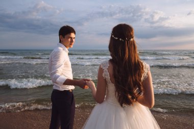 Zarif güzel gelin ve damat okyanus sahilde günbatımı süre boyunca yürüyüş. Tropik adada romantik yürüyüş yeni evliler