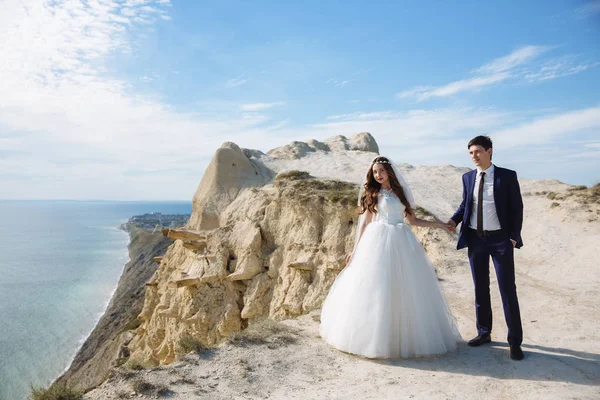 Sposo in abito elegante e sposa in abito bianco al matrimoniogiorno sulla scogliera con bella vista sull'oceano — Foto Stock