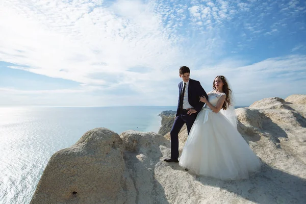 Sposo in abito elegante e sposa in abito bianco al matrimoniogiorno sulla scogliera con bella vista sull'oceano — Foto Stock