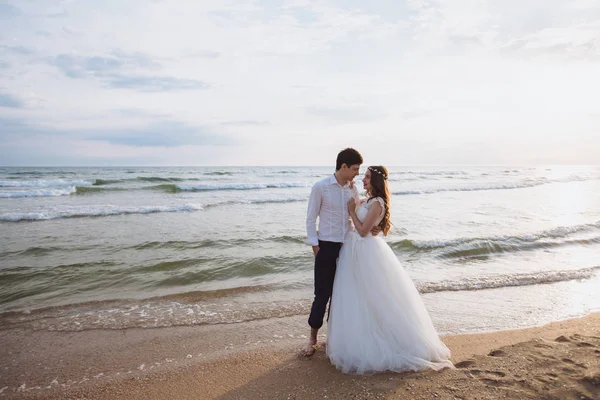 Bella giovane coppia appena sposata in piedi sulla spiaggia dell'oceano. Sposi trascorrere del tempo insieme, abbracciare e baciare — Foto Stock