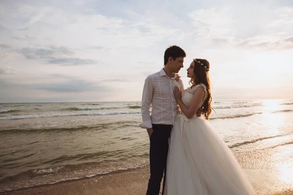 Bella giovane coppia appena sposata in piedi sulla spiaggia dell'oceano. Sposi trascorrere del tempo insieme, abbracciare e baciare — Foto Stock