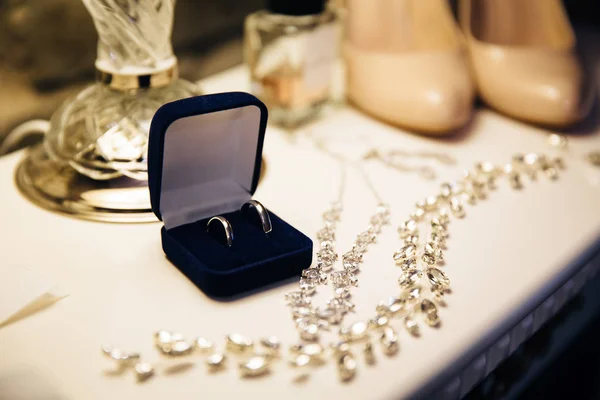 Brides set of wedding accessories, shoes, perfume and golden rings on the white table. Concept of jewellery.