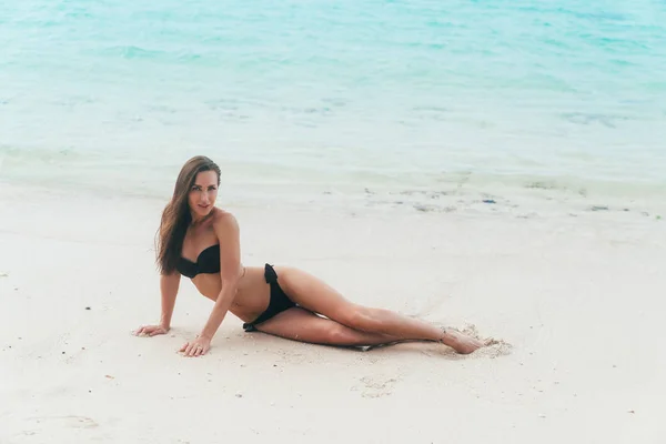 白い砂浜で横になっている水着でセクシーなモデル。女の子は、はだしし、熱帯の島に休暇にかかっています。 — ストック写真