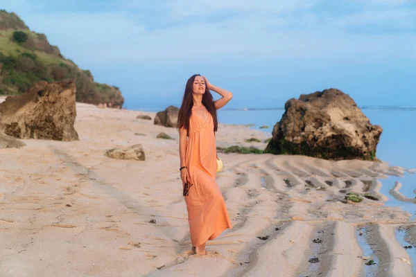 Hermosa chica feliz en sundress y con bolsa en correa larga posando en la playa de arena — Foto de Stock