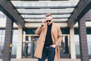 Genç adam modern saç modeli ve trendy ceket ayakta iş merkezi yakınlarındaki sakallı