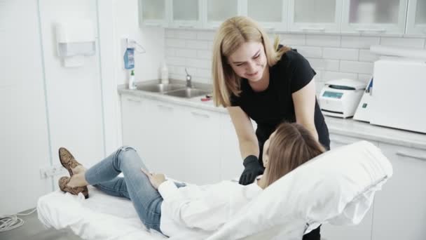 Kozmetikus megvizsgálja a beteg arca előtt eljárást. Fiatal lány, a recepció, a kozmetikus — Stock videók