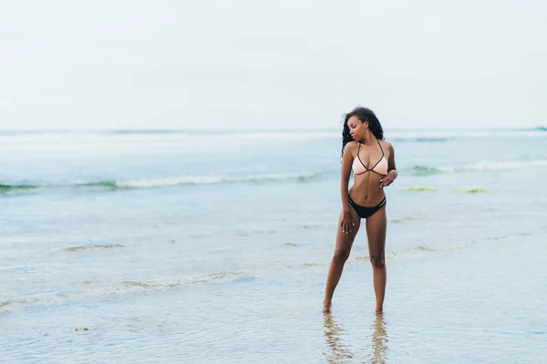 Vackra mörka flådda flicka i badkläder vilar på stranden. Afroamerikanska modell poserar på tropisk ö — Stockfoto