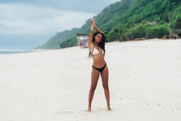 Esbelta chica sexy de piel oscura en traje de baño posando en la playa con arena. Mujer afroamericana descansando en la isla paradisíaca — Foto de Stock