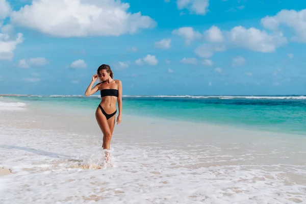 Girl with sexy body in swimwear sunbathes on white sand beach — Stock Photo, Image