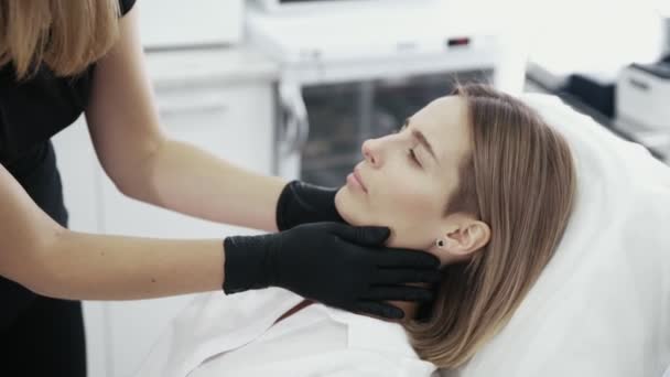 Закрыть руки косметолога осматривает и касается лица пациента . — стоковое видео