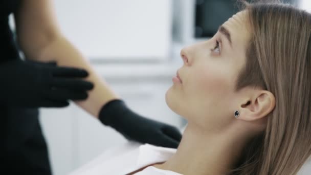 Detailní záběr mladá žena ukazuje kosmetička oblasti na její tvář pro injekce a léčba — Stock video